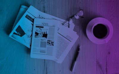 News paper, glasses, a pen, and a coffee mug on a table top