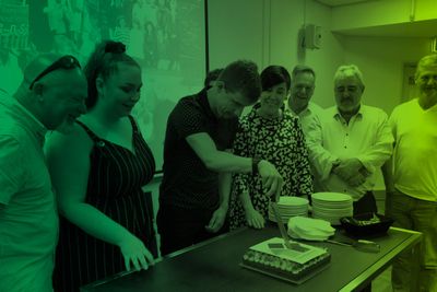 Man cutting cake while others watch.